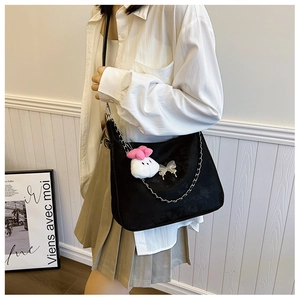 Detail of black hobo bag with silver chain and cute white bunny charm on a model