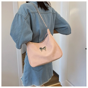 Detailed view of pink crossbody bag featuring a silver butterfly buckle and chain strap