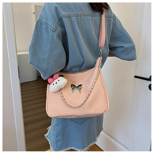 Close-up of pink crossbody bag with silver butterfly emblem and white plush charm