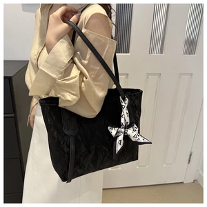 Detail der schwarzen Shopper-Tasche mit Knitter-Struktur und elegantem bedrucktem Seidenschal