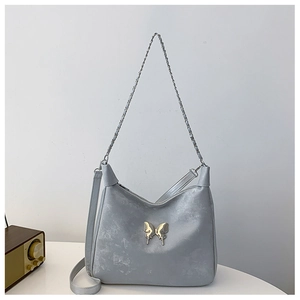 Detail of silver butterfly buckle and distressed leather texture on crossbody shoulder bag