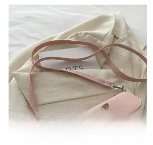 Detalle de bolso bandolera rosa con hebilla de lazo metálico y correa ajustable