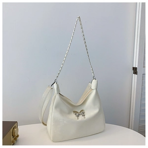Detail of white glossy shoulder bag featuring silver butterfly buckle and chain strap
