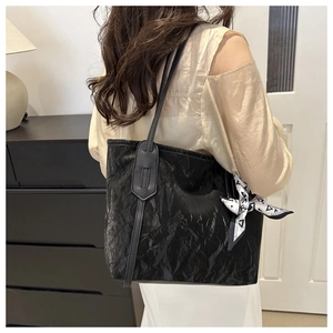 Detail of black tote bag featuring textured pleated leather and decorative silk scarf