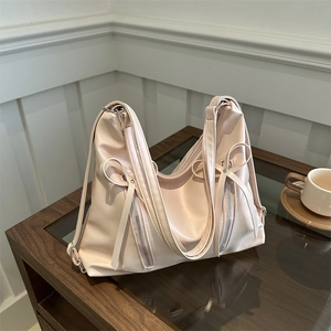 Sac bandoulière rose avec nœuds et fermetures éclair latérales en similicuir doux