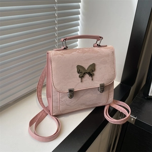 Pink vintage style backpack with textured fabric and metallic butterfly buckle detail