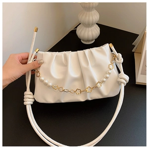 Detail of white pleated shoulder bag with pearl and gold flower chain decoration
