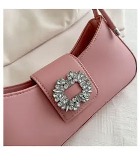 Close-up of the elegant rhinestone buckle on a pink leather shoulder bag detail