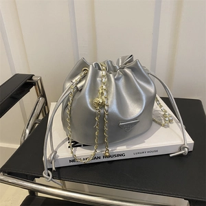 Silver metallic drawstring bucket bag with gold chain strap and triangle logo detail