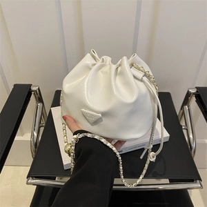 Minimalist white drawstring bucket bag with gold chain strap and triangle logo charm