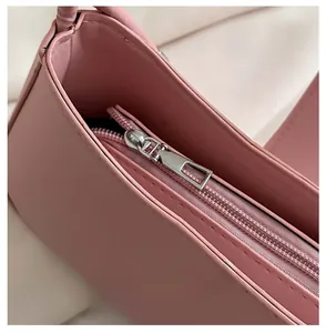Close-up of pink leather shoulder bag with smooth silver metal zipper closure