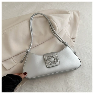 Detailed view of silver underarm bag with square rhinestone buckle and knot strap detail