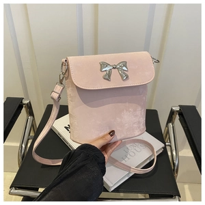 Detalle de bolso saco de ante rosa con un lazo metálico plateado y correa de hombro