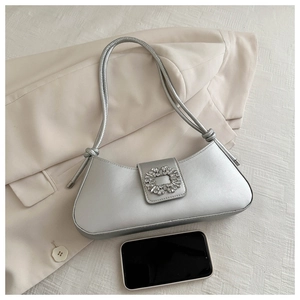 Detail of silver bucket bag with sparkling rhinestone square buckle on blazer background