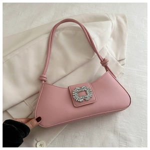 Close-up of pink baguette bag with sparkling crystal buckle on a white blazer background