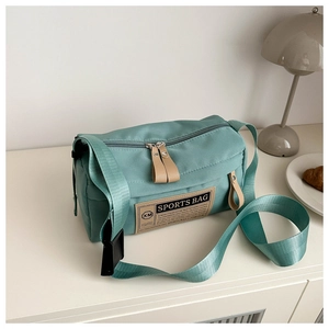 Detail shot of green nylon sports bag with contrast logo patch and premium leather zipper