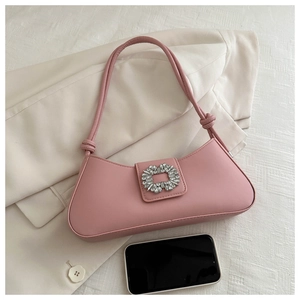 Detailed view of pink shoulder bag featuring a luxury rhinestone buckle and knot strap detail