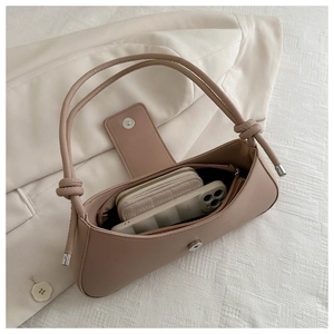 Detail of nude pink faux leather baguette bag showing spacious interior and knot strap
