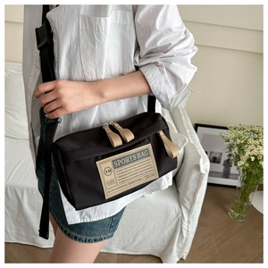 Close-up of black oxford cloth sports bag with wide shoulder strap worn by model
