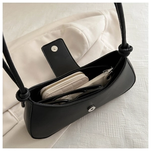 Interior view of black minimalist underarm bag showing capacity for wallet and sunglasses