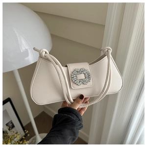 Close-up of creamy white leather handbag featuring a sparkling crystal rectangle buckle