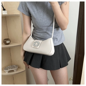 Detail view of a beige faux leather shoulder bag with a sparkling square rhinestone buckle