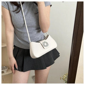 White leather underarm bag with a large crystal buckle shown in a mirror selfie perspective