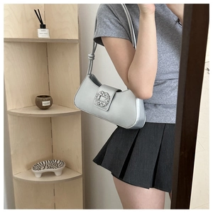 Detail of silver satin baguette bag featuring a sparkling rhinestone buckle and slim strap