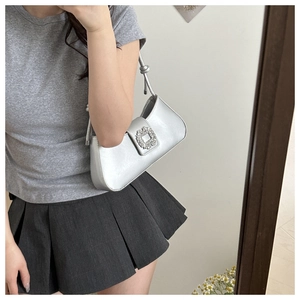 Detail of silver underarm bag featuring a large crystal buckle and knotted strap