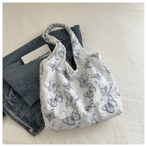 Detailed plush texture of white tote bag with blue butterfly prints and handle