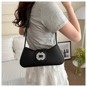 Chic black underarm bag with a crystal buckle shown in a modern interior setting
