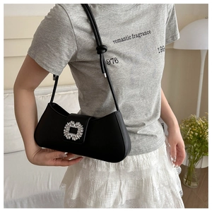 Detail of a black leather underarm bag with a sparkling silver rhinestone buckle decoration