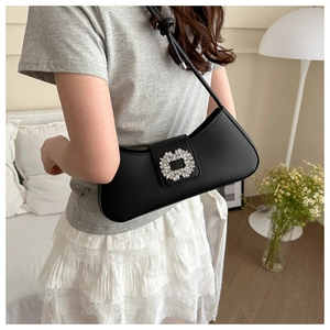 Detailed view of black leather underarm bag featuring a sparkling crystal rectangle buckle