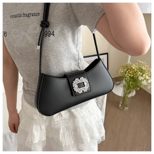 Close-up of black leather underarm bag featuring a signature square crystal buckle
