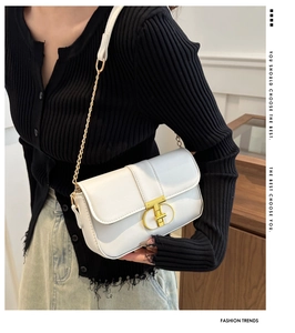 Detail of white leather crossbody bag featuring a golden T-ring buckle and chain strap