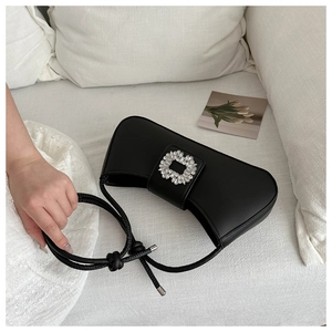Detailed close-up of a black matte leather baguette bag with a crystal buckle decoration