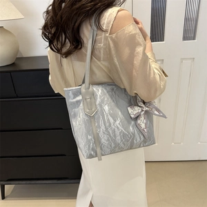 Silver-grey tote bag with pleated texture and decorative silk scarf shown on shoulder