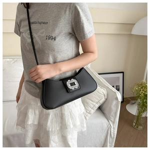 Close-up of black crossbody bag with decorative oversized rhinestone square buckle