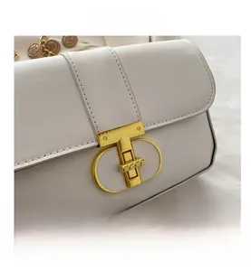 Close-up of golden T-shaped metal clasp on white PU leather handbag with stitching