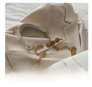 Close-up of a white leather handbag with golden chain and embossed portrait medallions