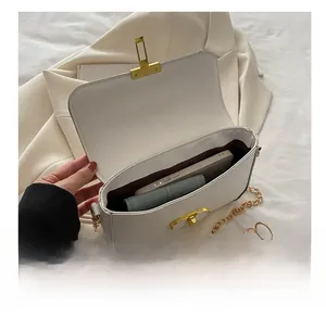 Top view of white compact square bag interior with gold buckle and chain strap