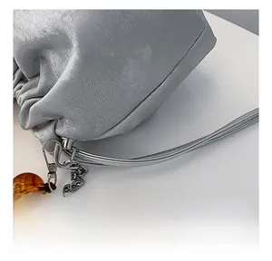 Détail du sac seau argenté avec cordon de serrage, chaîne et breloque en perle ambre