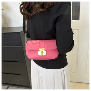 Close-up of hot pink leather crossbody bag with golden chain strap and T-shaped metal buckle