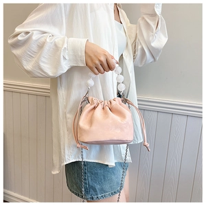 Détail du sac seau rose clair à cordon avec poignée en perles blanches et chaîne en métal