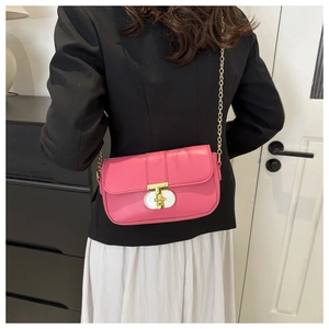Pink crossbody bag with gold chain strap and T-shaped metal buckle on a stylish model