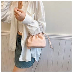 Détail du sac seau rose à cordon avec une grande poignée en perles et une chaîne en métal