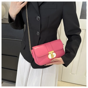 Detail of bright pink square crossbody bag featuring a golden T-shaped clasp and chain strap