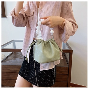 Détail du sac seau plissé vert clair avec anse en perles et bandoulière en chaîne