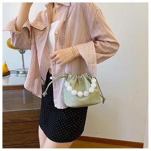 Détail du sac seau vert clair avec poignée en perles de marbre et chaîne en argent