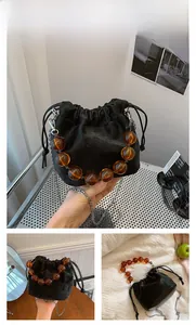 Détail du sac seau en velours noir avec poignée en résine ambrée et bandoulière chaîne
